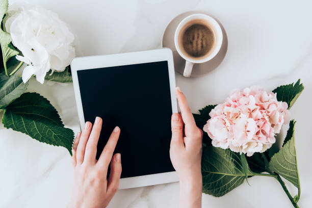 istock cropped view of woman using digital tablet with blank screen on tabletop with espresso coffee and  hortensia flowers 1016042996