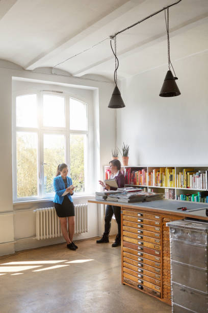 istock Businesswomen discussing by bookshelf in office 1016043096