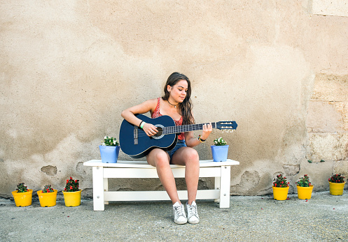Beautiful brunette playing guitar outdoors.
