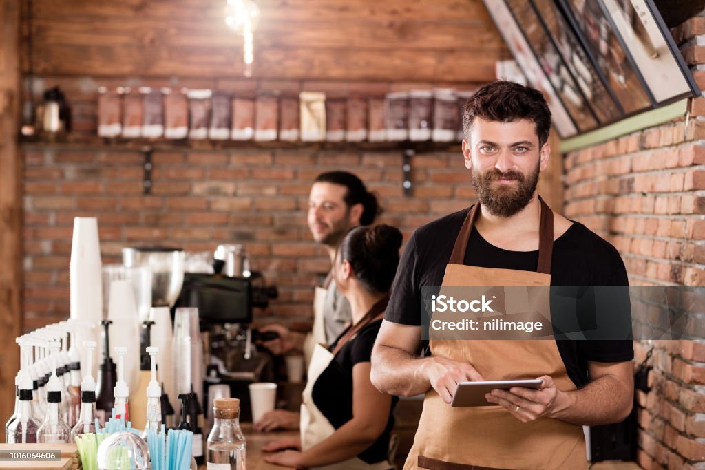 Young Cafe Owner Young cafe owner posing with laptop. Restaurant Stock Photo