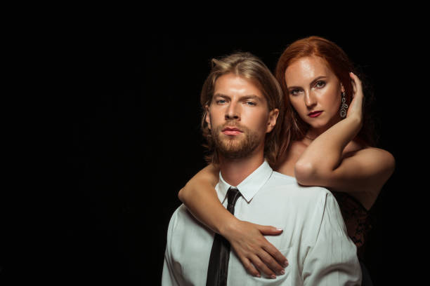 istock Real passion. Beautiful young loving couple bonding to each other while both standing against black studio walls 1016065388