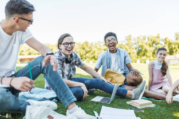 istock happy multiethnic teenagers sitting and laughing while studying together in park 1016067824
