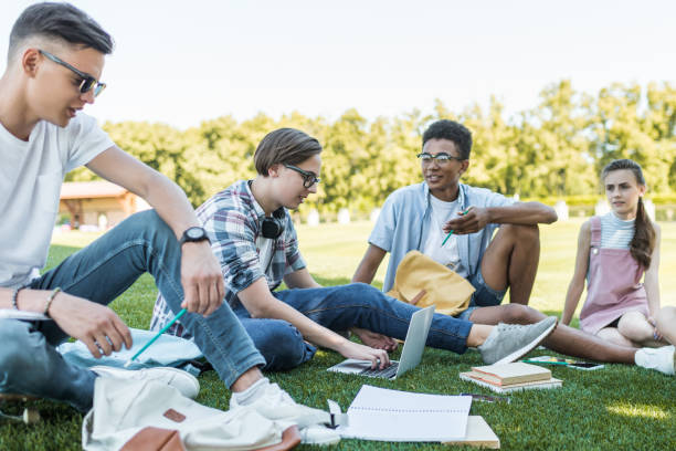 istock happy multiethnic teenagers sitting and talking while studying together in park 1016067866