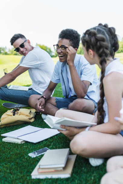 istock happy multiethnic teenage students smiling while studying together in park 1016070302