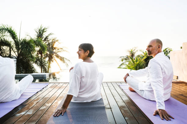 istock Group of seniors practicing yoga by the pool 1016070576