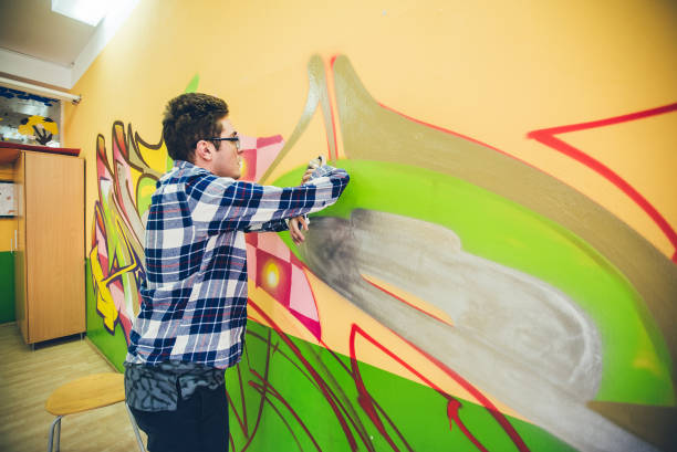 istock Man painting graffiti on orange wall 1016073862