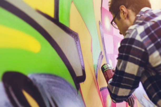 istock Man painting graffiti on orange wall 1016074486