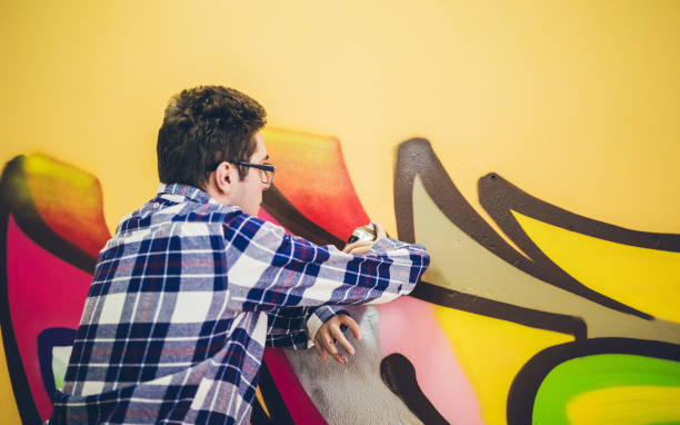 istock Man painting graffiti on orange wall 1016074760