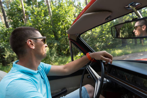 istock A man riding on a retro convertible. 1016077374