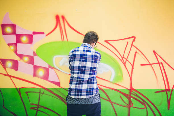 istock Man painting graffiti on orange wall 1016077804