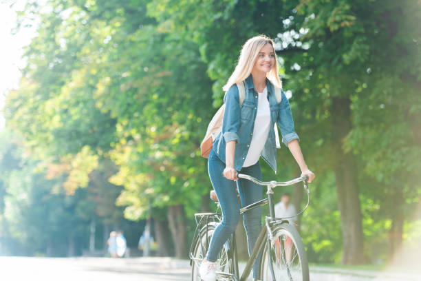 istock smiling student with backpack riding bicycle on street 1016087596