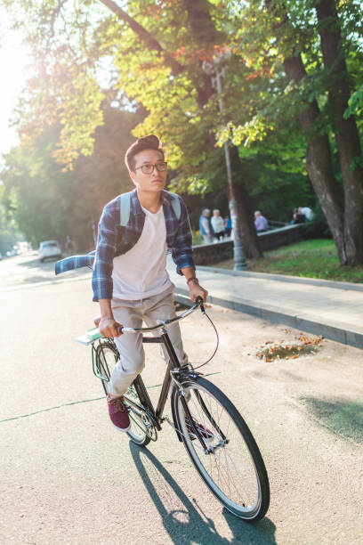 istock asian student in eyeglasses with backpack riding bicycle on street 1016102740