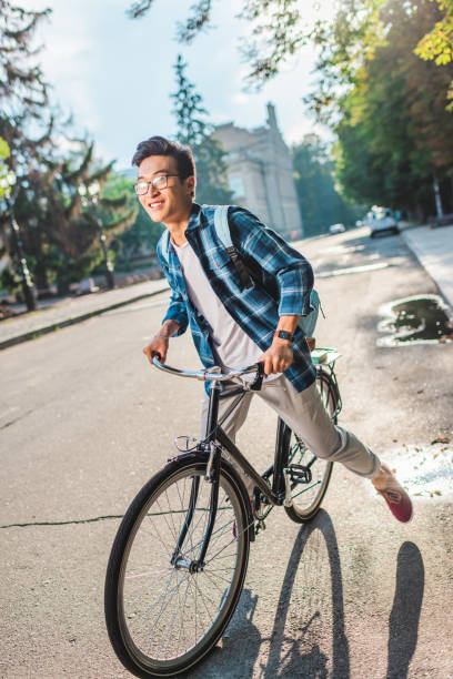 istock smiling asian student in eyeglasses with backpack riding bicycle on street 1016102764