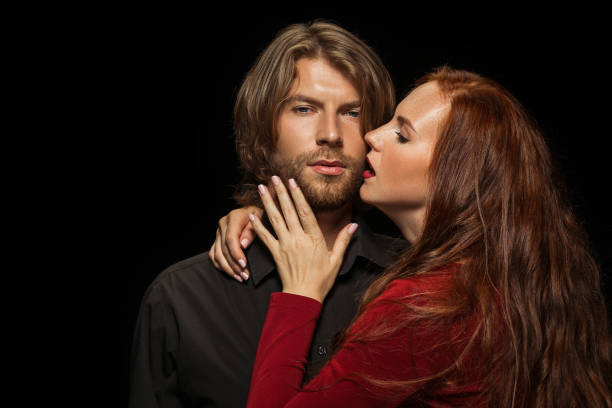 istock Real passion. Beautiful young loving couple bonding to each other while both standing against black studio walls 1016112390