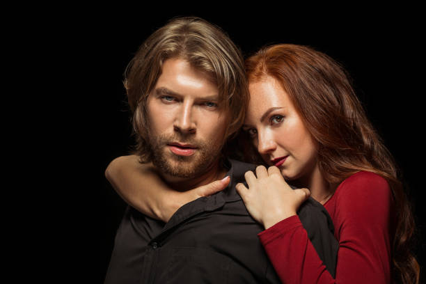 istock Real passion. Beautiful young loving couple bonding to each other while both standing against black studio walls 1016112566