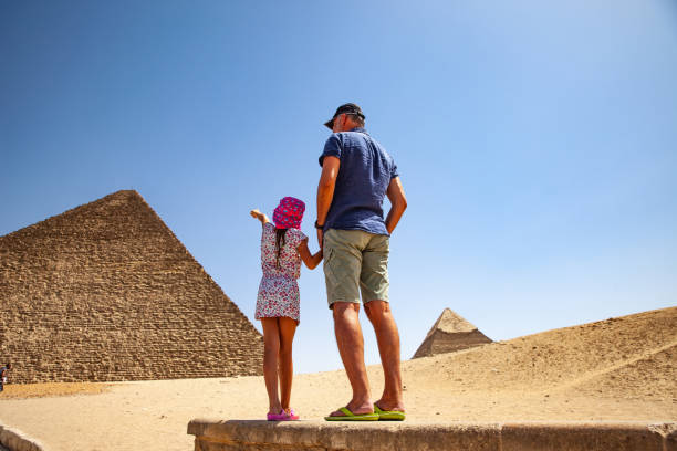 отец и дочь глядя на пирамиду хеопса в гизе - tourist egypt pyramid pyramid shape стоковые фото и изображения