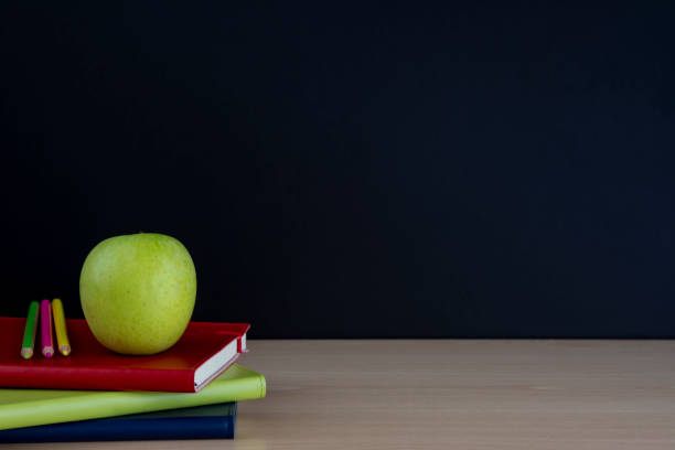 istock green apple on books with pencils and empty blackboard, back to school 1016124972