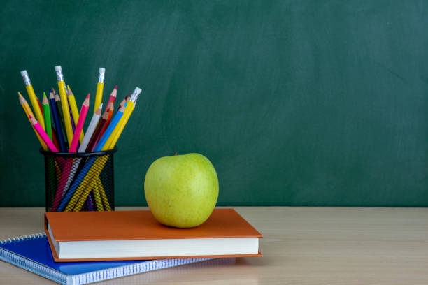 istock Pencil on table and green  apple on book with blackboard  as background with copy space. 1016124988