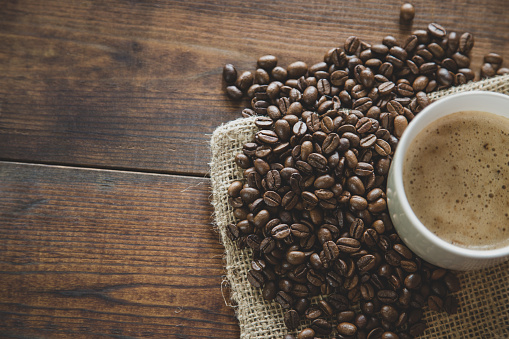 A cup of espresso coffee with coffee beans on wooden background