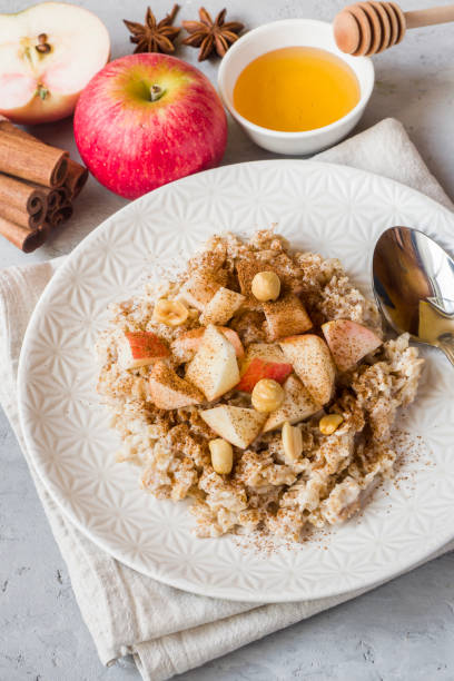 istock Oatmeal with fresh apples, nuts and cinnamon for Breakfast on the table, close-up, vertical 1016152514