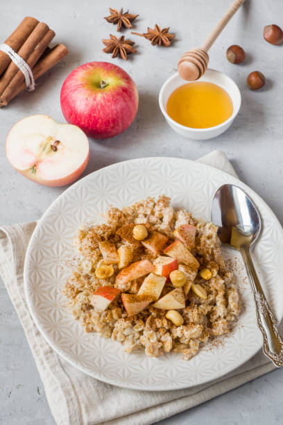 istock Oatmeal with fresh apples, nuts and cinnamon for Breakfast on the table, close-up, vertical 1016152884