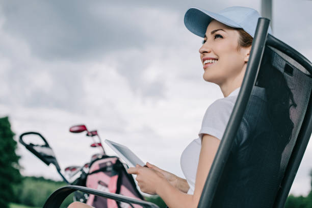 istock low angle view of cheerful female golf player in cap with tablet in hands 1016165002