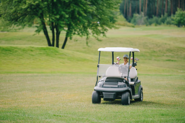 femme en voiturette de golf de circonscription de cap au terrain de golf le jour de l’été - golf cart golf mode of transport transportation photos et images de collection