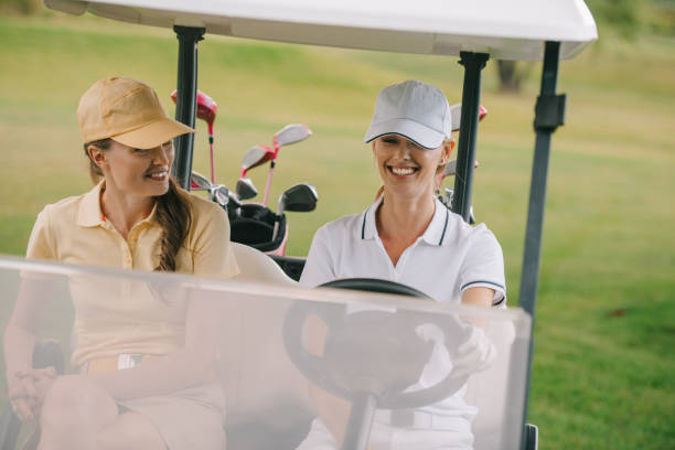 istock smiling female golf players riding golf cart at golf course 1016168208