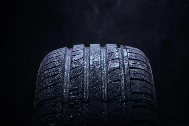 Photo of Water splashing on a new symmetrical tire during the rain