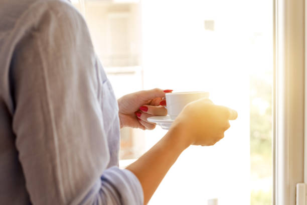 istock Woman and coffee in hands looking from window 1016173616