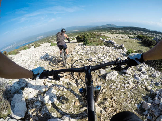 Man and woman mountain biking above the sea point of view stock photo