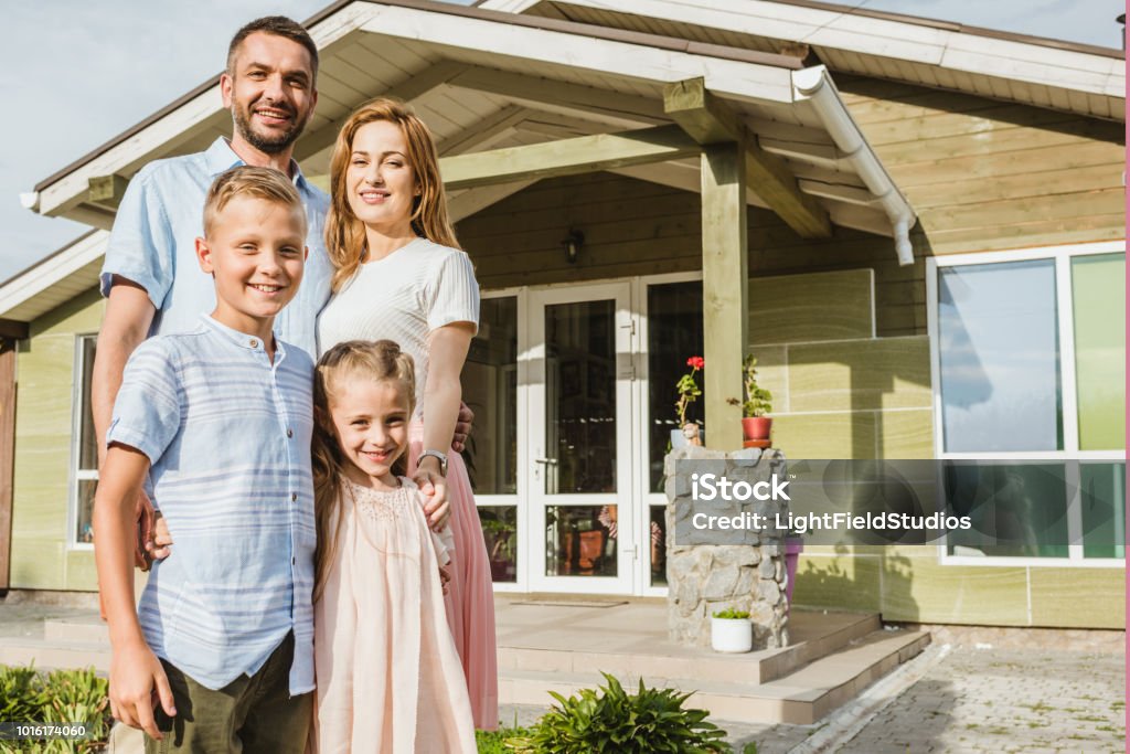 smiling parents and children standing in front of house Family Stock Photo