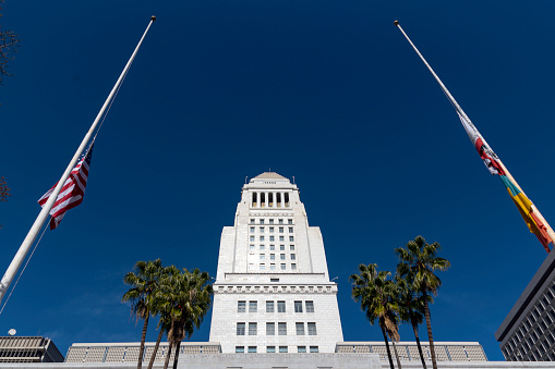 Los Angeles City Hall, tall historic building framed by flag poles, March 2, 2017, Los Angeles, California, USA