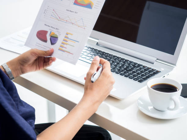 istock Businesswoman working in office, reading a financial report/documents using laptop and drink coffee and during  business meeting 1016189868