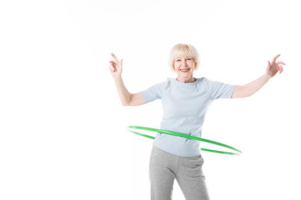 istock Smiling senior sportswoman doing hula hoop exercise isolated on white 1016207836