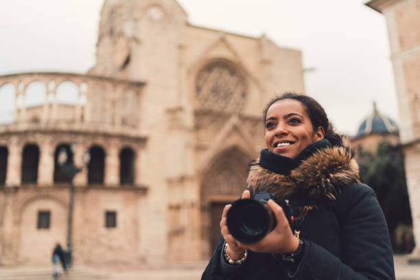 Mixed race woman traveling single in Europe,Plaza de la Virgen,Valencia Smiling woman with camera exploring Valencia explorer photos stock pictures, royalty-free photos & images