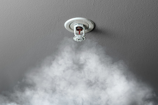 fire alarm sprinkler system in action with smoke, close-up view