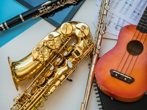 Variety of musical instruments, digital tablet and sheet music against the multi colored background.