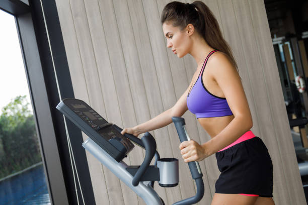 deportiva mujer con entrenador elíptico - ellipse elliptical format exercising women fotografías e imágenes de stock