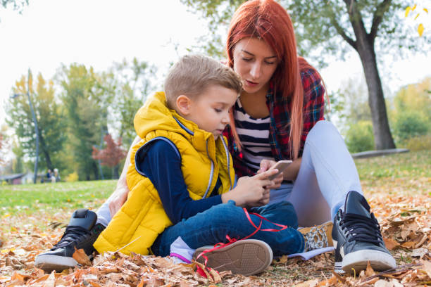 istock Mother and son using mobile phone in autumn park. 1016242164
