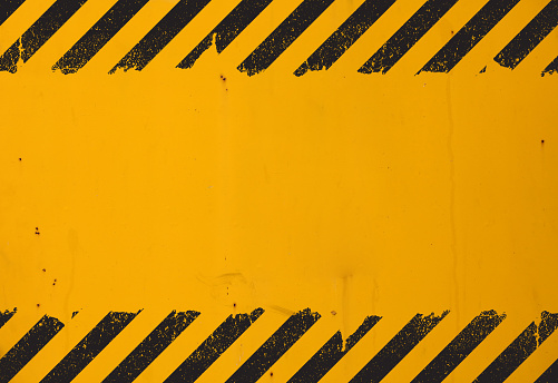 Old yellow weathered painted background with grunge black hazard sign stripes and copy space