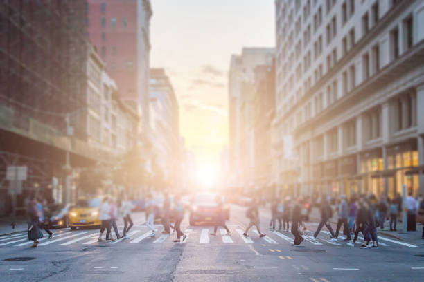 Anonymous crowd of people cross the intersection on a busy New York City street in Manhattan Anonymous crowd of people cross the intersection on a busy New York City street in Manhattan with sunlight background car city urban scene commuter stock pictures, royalty-free photos & images