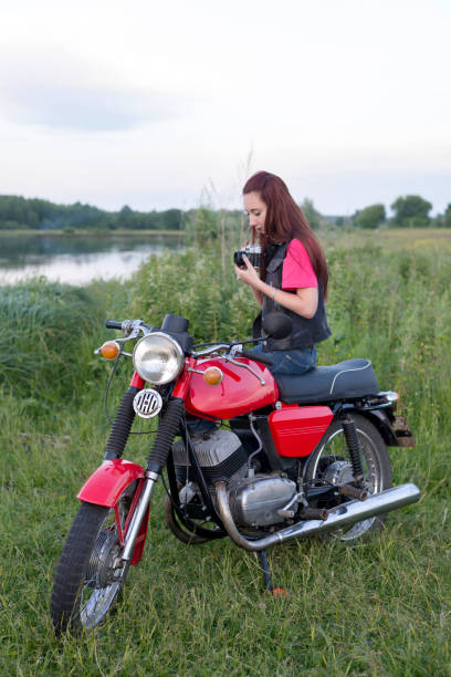 istock Girl sitting on a vintage motorcycle with a camera 1016245958