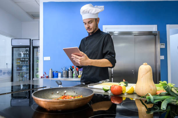istock young chef by referring to a Smartphone or tablet in a professional kitchen 1016248544