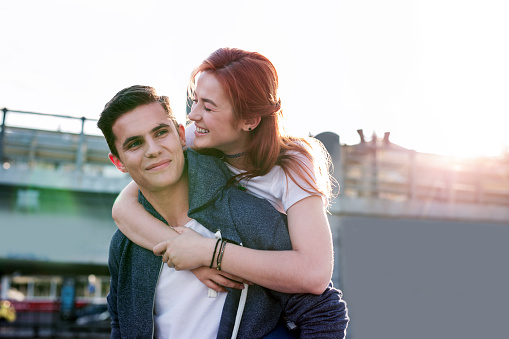 Love story. Pretty young woman smiling while hugging her boyfriend