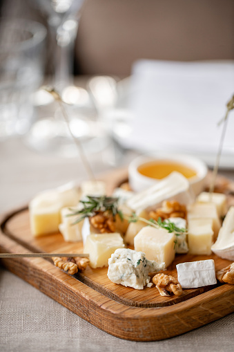 Cheese plate. Delicious cheese mix with walnuts, honey, grapes on wooden table. Tasting dish on a wooden plate. Food for wine