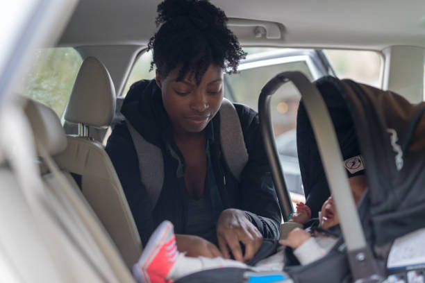 mom puts her infant baby into the carseat - car baby baby car seat child imagens e fotografias de stock