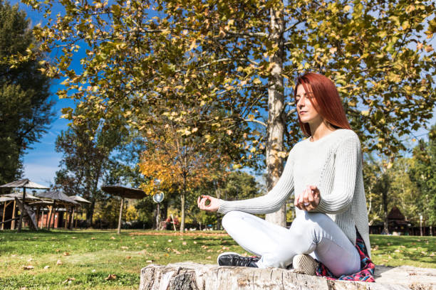 spokojna kobieta medytuje w parku. - zen like nature breathing exercise sitting zdjęcia i obrazy z banku zdjęć