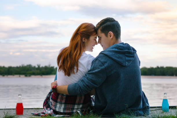istock Joyful happy couple sitting near the river 1016276488