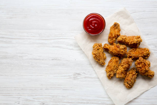 istock Fried chicken wings with ketchup on a white wooden surface, top view. From above, overhead. Copy space. 1016276524
